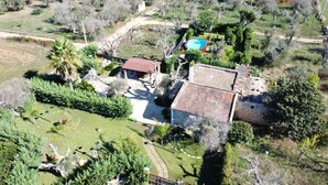 Vue aérienne d’une propriété dotée d’une piscine, d’un jardin clôturé et d’un bâtiment en pierre.