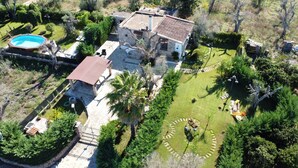 Vue aérienne d’une propriété comprenant une piscine, un bâtiment en pierre et un jardin circulaire.