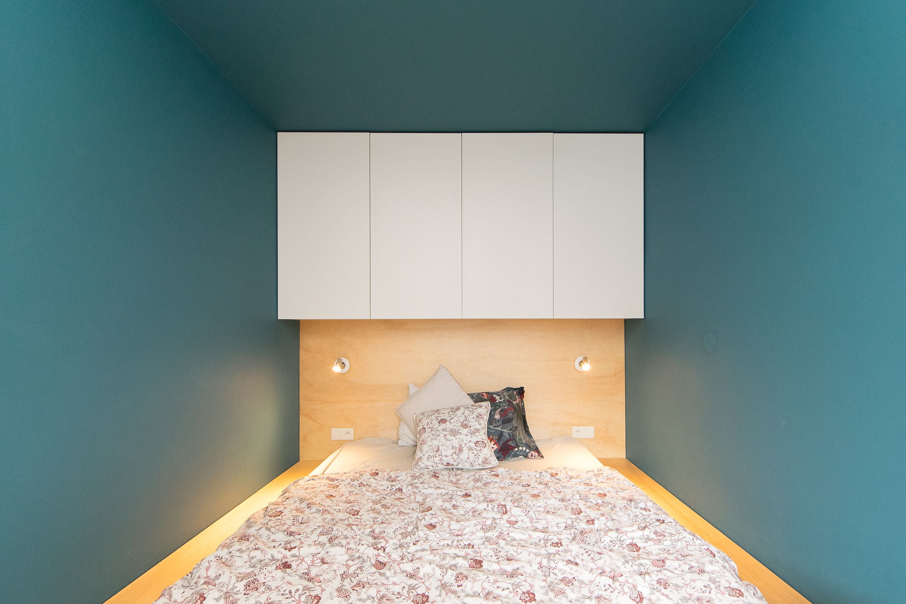 Een slaapkamer met een bed, hoofdbord en een kledingkast.