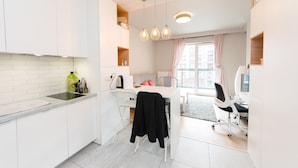 Une cuisine moderne avec des meubles blancs, un plan de travail noir et un coin repas comprenant une table et des chaises blanches.