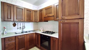 Una cucina con mobili in legno, un lavello in acciaio inossidabile, un fornello a gas e una lavastoviglie.
