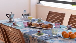 A dining table set with pastries, a coffee pot, and cups.