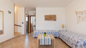 A room with a bed, a small table with a striped tablecloth, and a wall-mounted artwork.