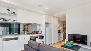 Una cocina moderna con armarios blancos, horno empotrado, microondas y refrigerador.