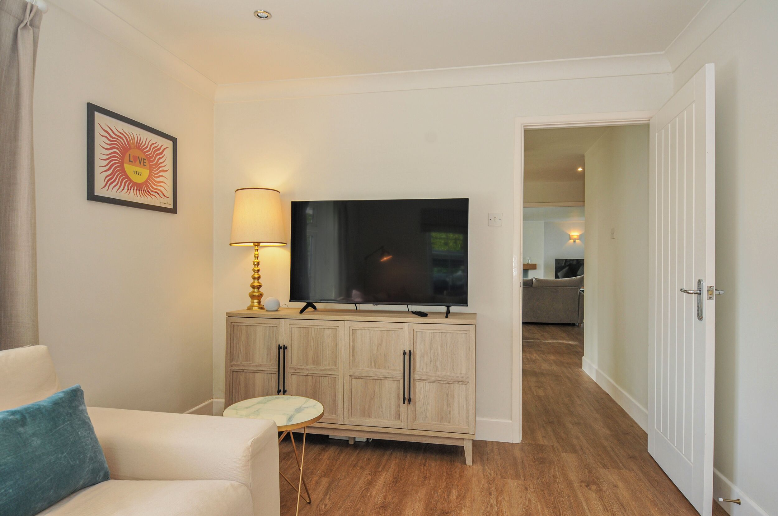 A living room with a TV, a lamp, a sofa, and a cabinet.