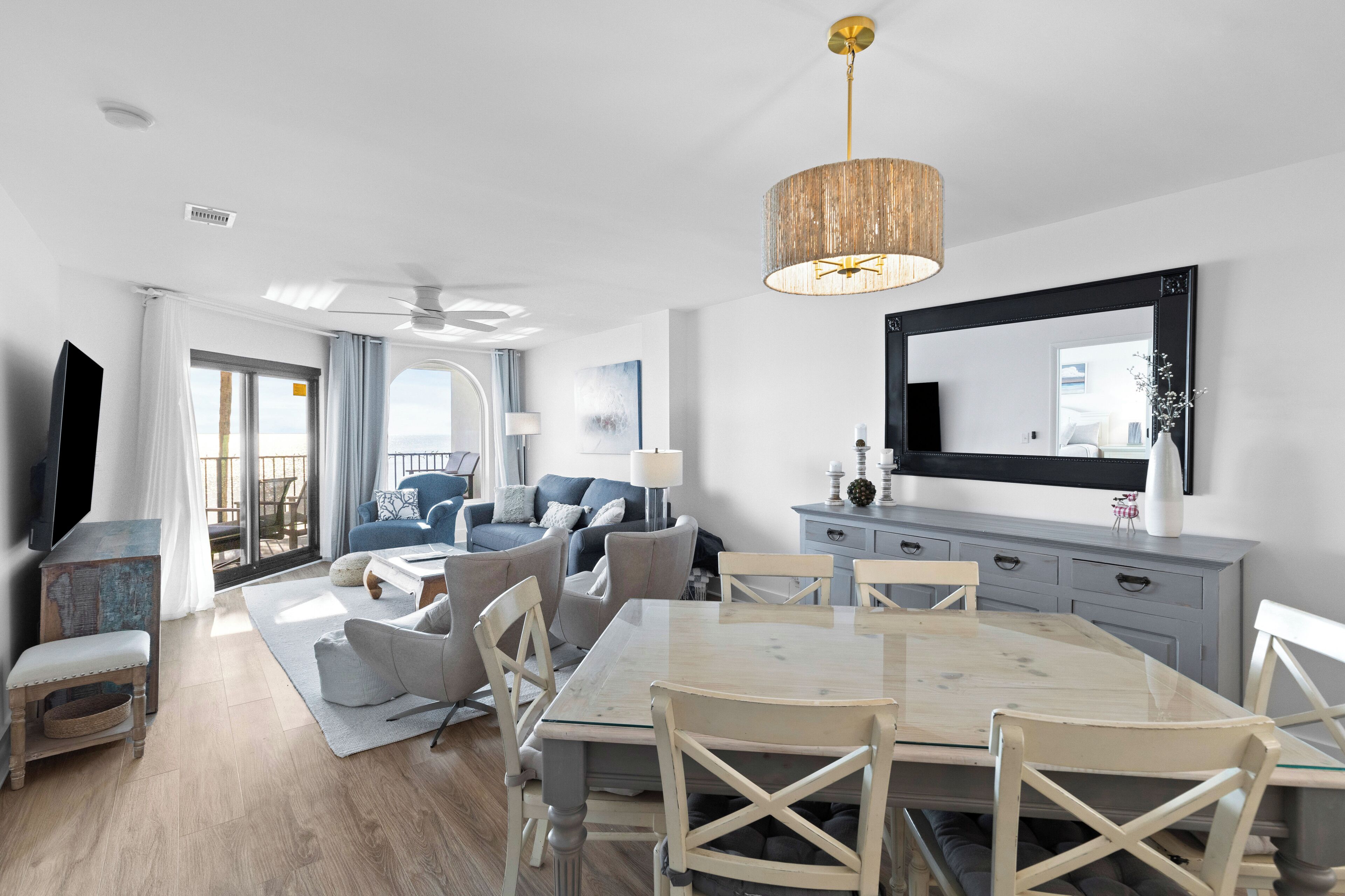 A modern living room with a dining area, a large mirror, and a television.