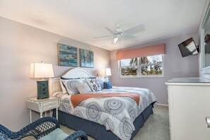 A bedroom with a bed, nightstands, a chair, a dresser, a ceiling fan, and artwork on the walls.