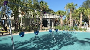A playground with swings and a palm tree-lined background. - Condo#203 Updated beautiful  condo on Siesta Key with an upscale comfortable coastal look and feel. (Sarasota)