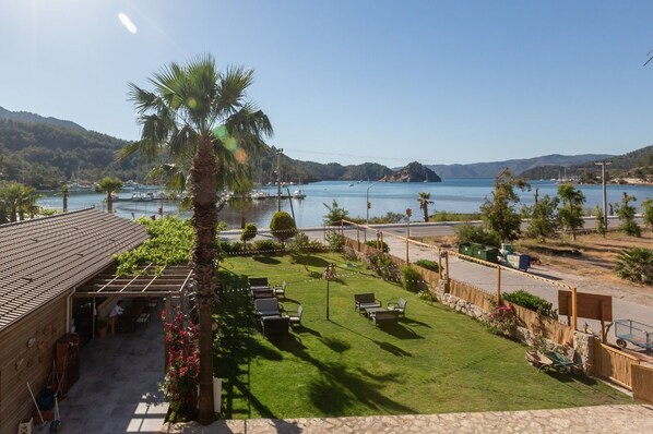 Vista de una propiedad costera con un patio, mobiliario exterior y vistas al mar y a las montañas.