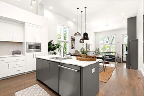 A modern kitchen with white cabinets, a large island, and pendant lighting. - 'Central Park' Home｜Vandy-3 blocks｜Broadway-2.5mi (Nashville)