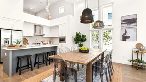 Une cuisine spacieuse dotée d’un îlot central, d’appareils électroménagers modernes et de luminaires suspendus.