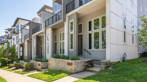 Une maison de ville moderne avec un toit plat, de grandes fenêtres et une pelouse bien entretenue.