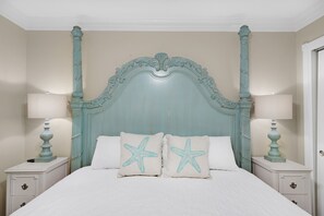 Un letto a baldacchino con cuscini a forma di stella, due comodini con lampade e una parete color crema.