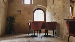 Un comedor rústico con paredes de piedra, un techo alto y abovedado, y una ventana que proporciona luz natural.