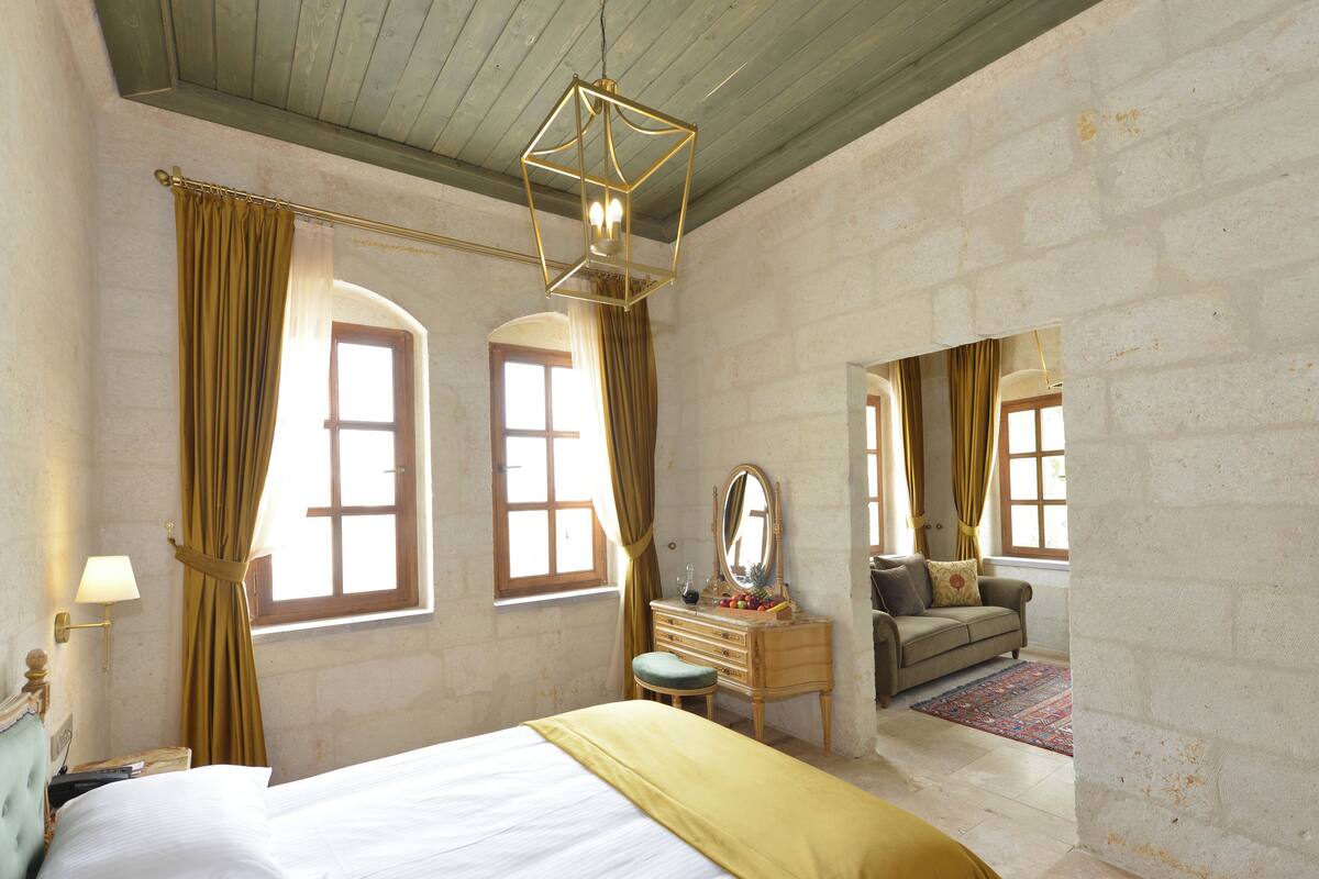 A bedroom with a large bed, a dresser, a mirror, and a view of another room through an arched window.