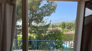 Ein Zimmer mit einer Schiebetür zu einer Terrasse. Die Terrasse hat ein blaues Geländer, einen Tisch und Stühle.