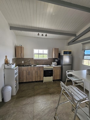 Enjoy cooking in this well-equipped kitchen with a central island, stove, oven, refrigerator, microwave, and sink.