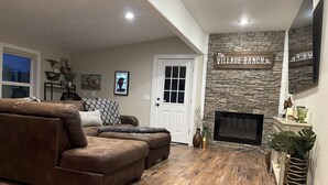 A living room with a stone fireplace, leather sofas, and a mounted TV.