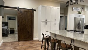 A kitchen with a large island, white cabinets, and a sliding barn door.