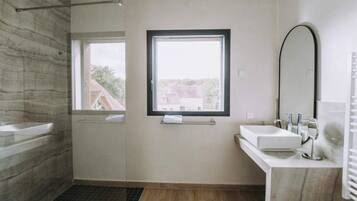 Een moderne badkamer met een groot raam, een badkuip, een wastafel en een spiegel.