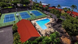 Uma quadra de tênis, uma piscina e vista para o oceano.