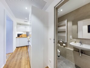 A modern kitchen with white cabinets, a wooden countertop, and a ceiling with perforated panels.