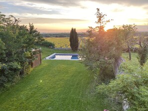 Un pati amb piscina, envoltat de vegetació abundant i vista del camp.