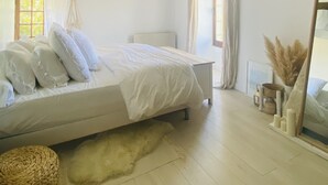 Un dormitorio con cama, techo de vigas de madera, ventana y espejo.