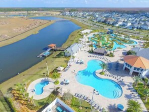 Een resort met diverse zwembaden, een waterpark en een steiger die in een meer uitloopt.