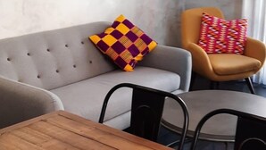 Un comedor con mesa de madera, sofá gris y sillón amarillo.
