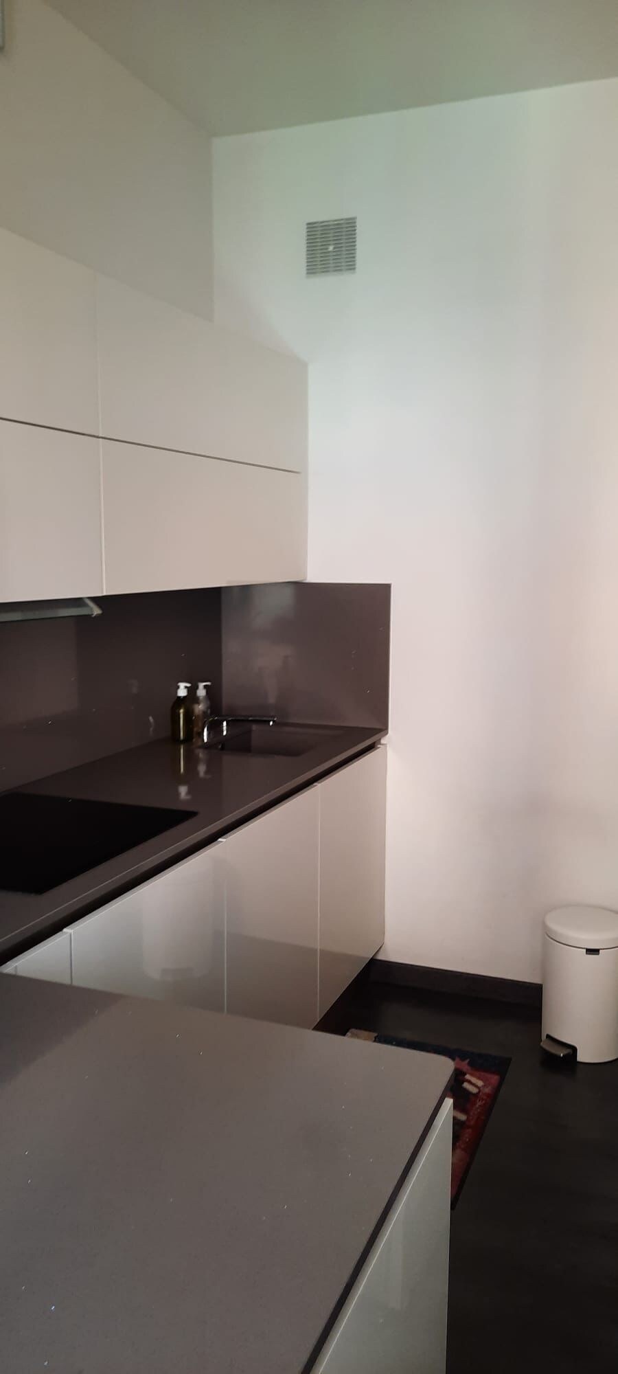 Ett kök med vita skåp, en svart bänkskiva och en vit papperskorg.