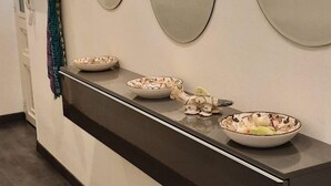 Un baño moderno con encimera negra, tres espejos redondos y un adorno en la pared.