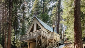 Eine Holzhütte mit Metalldach, einer Holzterrasse und einer Garage.