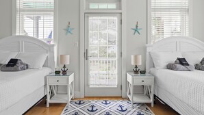 A bedroom with two beds, a door with a window, and a starfish decoration on the wall.