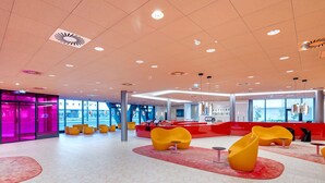 A modern lobby with a geometric floor pattern, bright lighting, and yellow seating areas. - Prize by Radisson, Vienna City (Vienna)
