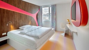 A modern bedroom with a bed, a TV mounted on the wall, and a window with curtains. - Prize by Radisson, Vienna City (Vienna)