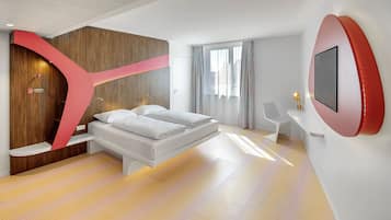 A modern hotel room with a bed, a desk, and a large mirror.