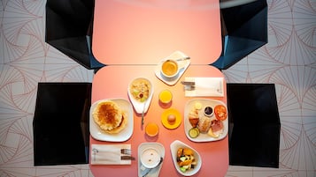 A breakfast table with various dishes including pancakes, eggs, and fruits.