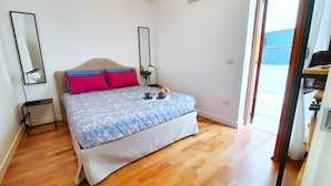 A bedroom with a bed, a bedside table, a lamp, and a window.