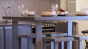A modern kitchen with grey cabinetry, a tiled backsplash, and a dining area with a table set for two.