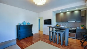 A modern kitchen with a dining area, wooden flooring, and a blue dresser.
