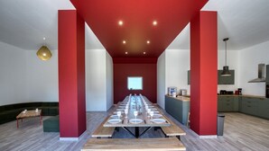 Een moderne vergaderruimte met een lange tafel gedekt voor een vergadering, een kitchenette en een zithoek met een groene bank.