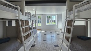 Een kamer met stapelbedden, een deur naar buiten en uitzicht op een tuin.