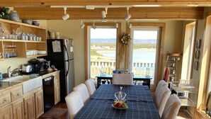 Un vaste espace dédié à la salle à manger, avec une longue table, des meubles en bois et une vue sur l’extérieur.