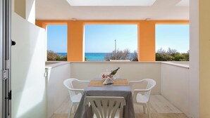 A balcony with a table and chairs, a bottle, and a view of the sea. - Residence Solaris - Bilo PP Fronte Mare (Torre Specchia Ruggeri)