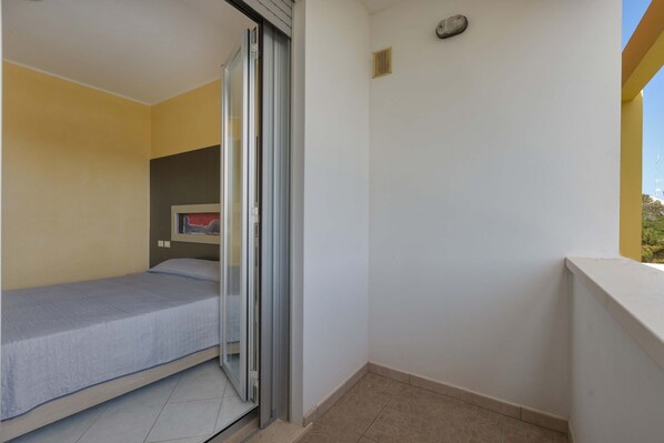 A small, single-room apartment with a sliding glass door leading to a balcony.