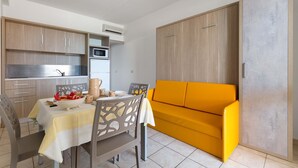 Un espacio habitable compacto con kitchenette, comedor y sofá.