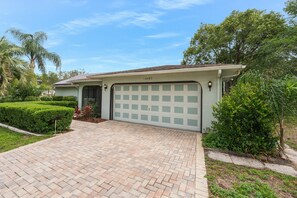 A residential house with a garage, paved driveway, and well-maintained landscaping.