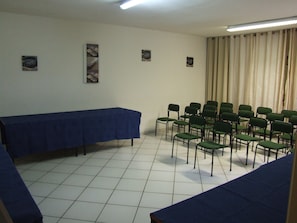 Conference room with a blue table and chairs, framed artwork, and a ceiling light fixture.