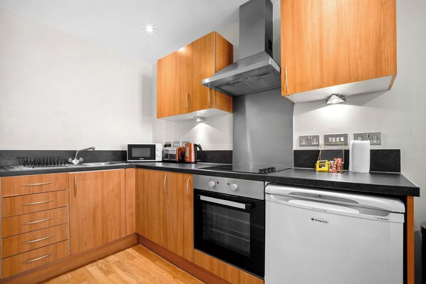 A modern kitchen with wooden cabinets, a stainless steel range hood, a built-in oven, and a dishwasher.